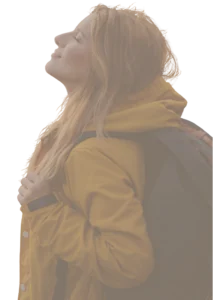 Pessoa de perfil com casaco amarelo e mochila cinza, olhos fechados e rosto voltado para o céu, expressando paz e contentamento. O fundo é branco neutro e bem iluminado.