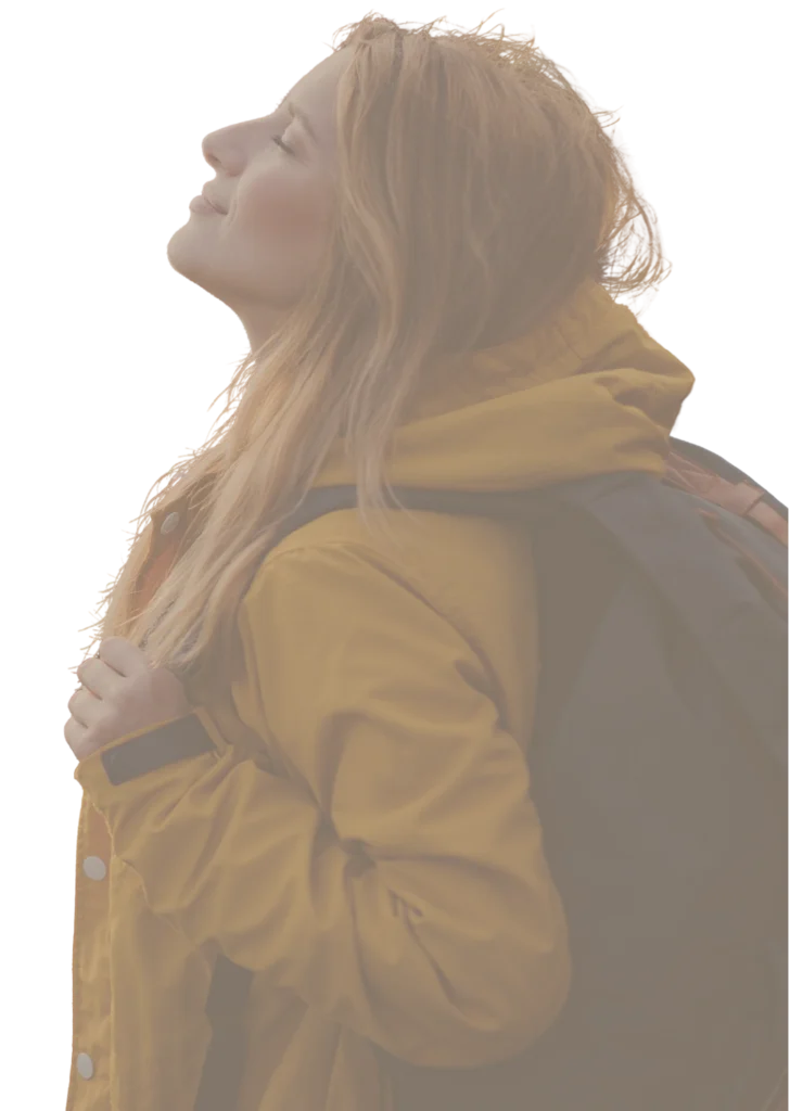 Pessoa de perfil com casaco amarelo e mochila cinza, olhos fechados e rosto voltado para o céu, expressando paz e contentamento. O fundo é branco neutro e bem iluminado.