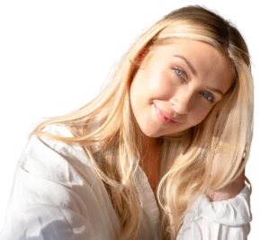 Retrato em close de uma mulher loira sorrindo suavemente, com iluminação solar lateral. Ela veste uma camisa branca de tecido leve. O fundo é branco e minimalista, transmitindo paz e clareza.